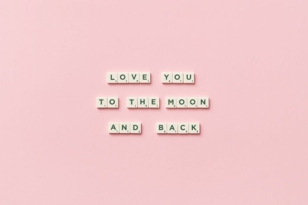 Letter tiles spelling 'Love You to the Moon and Back' on a pink background.