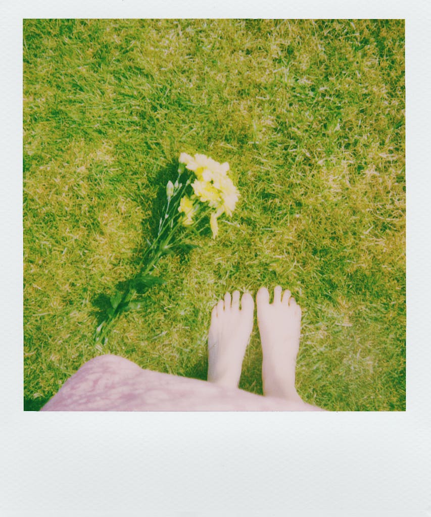 A serene top view of barefoot on lush green grass beside yellow flowers, capturing the essence of spring.