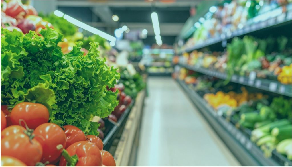 A softly blurred grocery store produce aisle with fresh vegetables, representing the everyday places where unexpected spiritual counseling moments unfold.