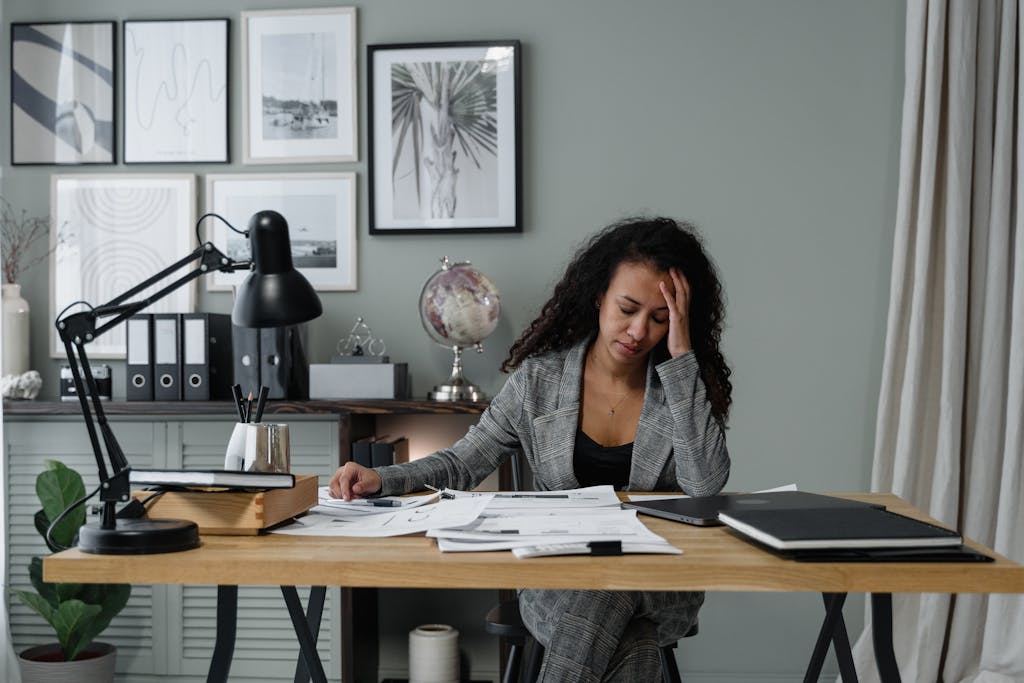 A woman overwhelmed at her desk, representing how many people today carry emotional and mental stress without support.