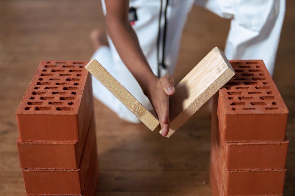 A martial artist breaking a wooden board supported by bricks during a karate demonstration.