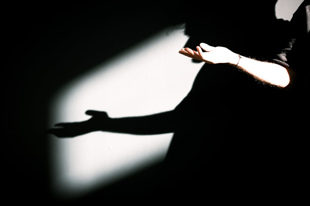 Artistic capture of hands and their shadows on a dark background.