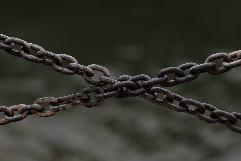 Close-up of crossed rusty chains over a blurred green background.