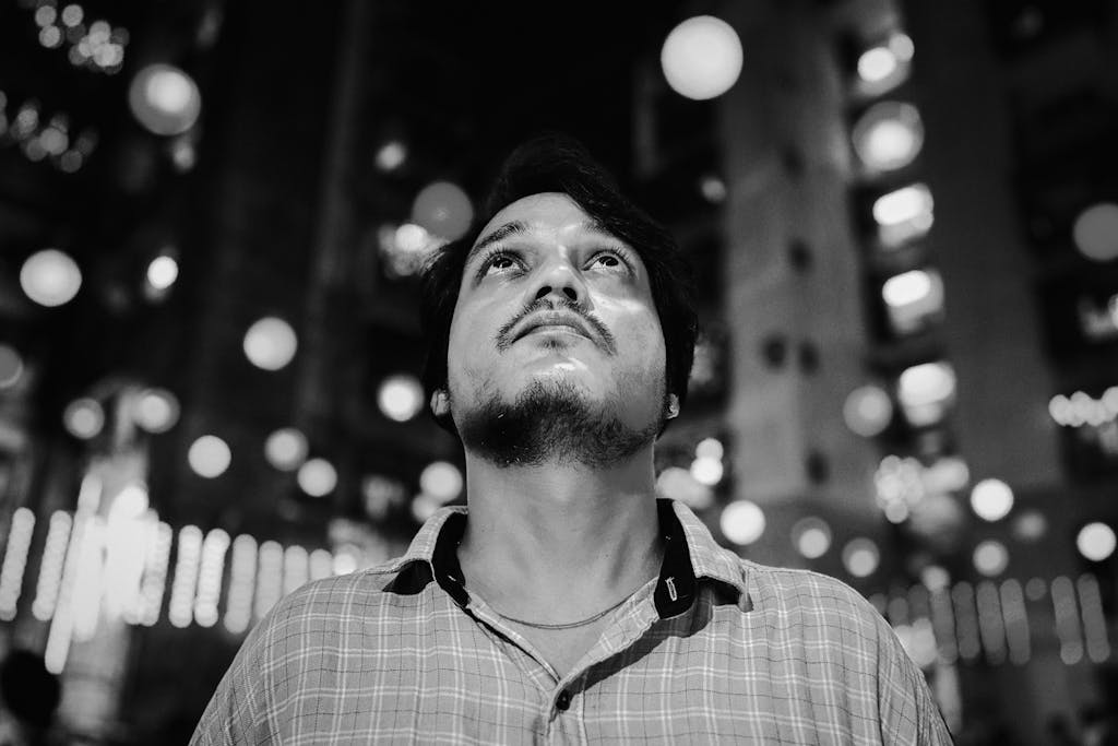 Portrait of a thoughtful man in Mumbai, India, captured amidst city lights in black and white.