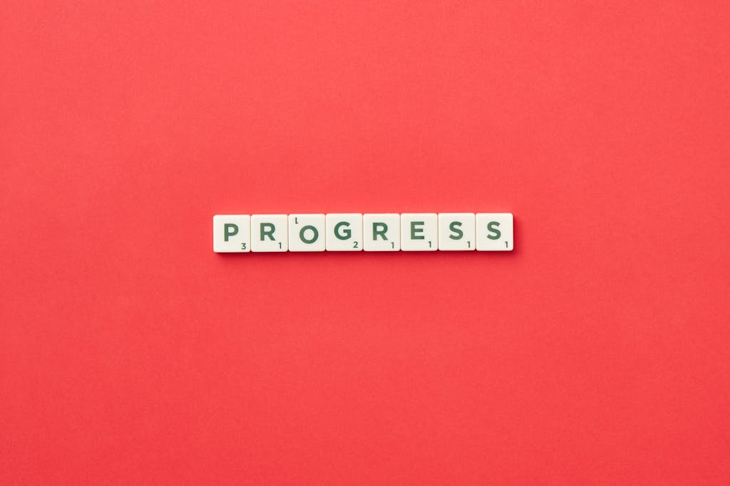 Scrabble tiles spelling 'Progress' on a vibrant red background, symbolizing development.
