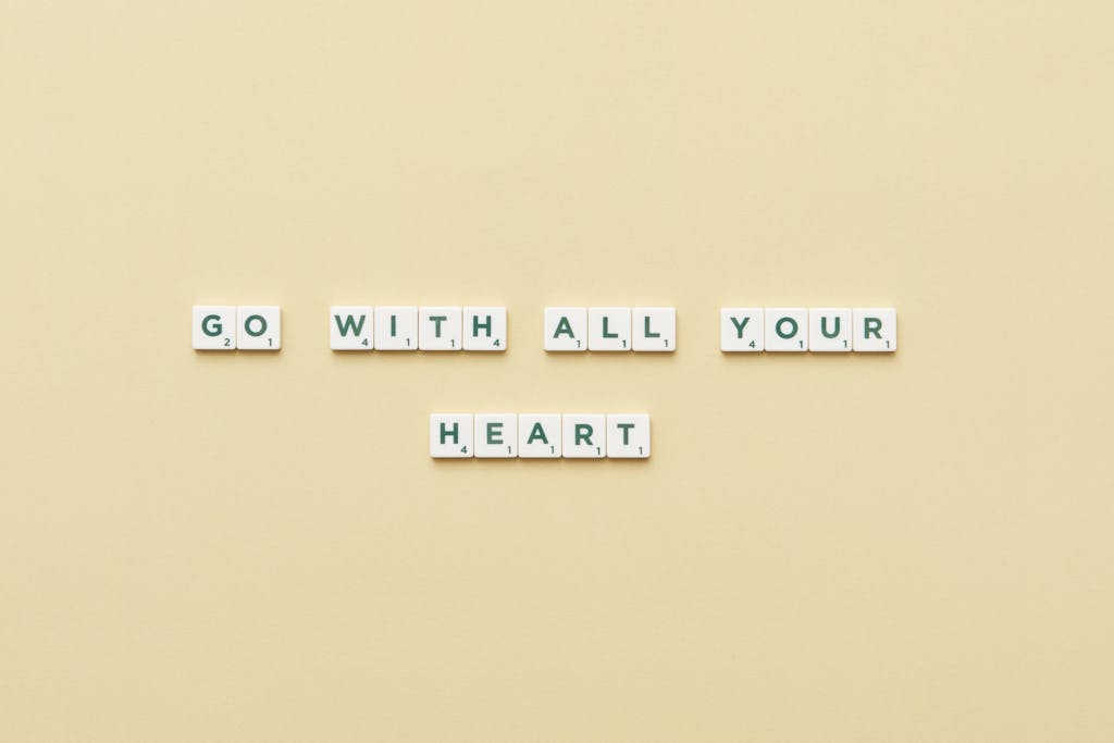 Motivational message 'Go With All Your Heart' displayed using Scrabble tiles on a beige background.
