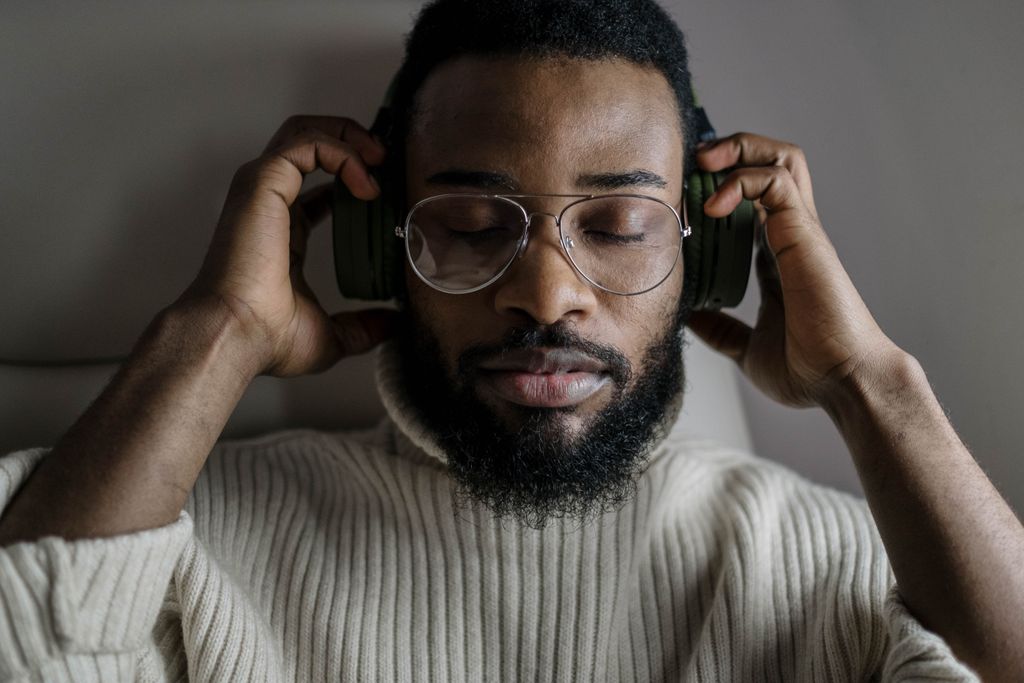 Close-up of a man relaxing with headphones on, eyes closed, enjoying music.